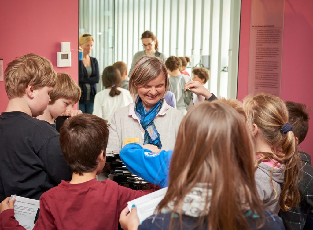 Museumspädagogin mit Schülerinnen und Schülern in der Ausstellung.