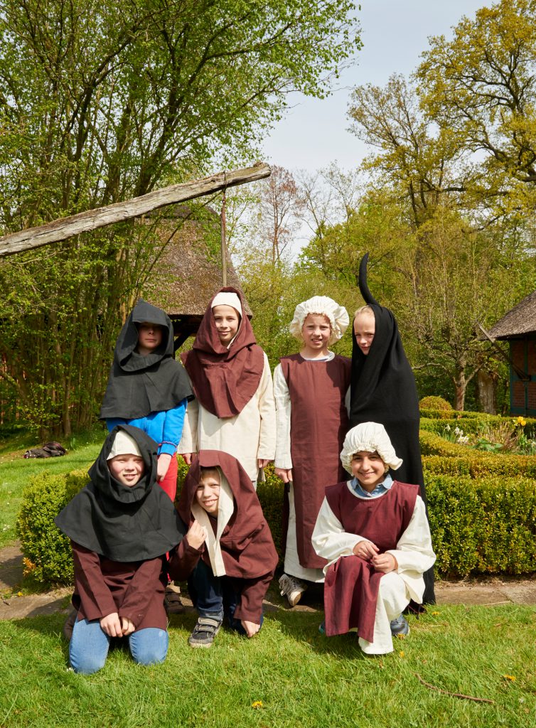 Kinder in mittelalterlichen bäuerlichen Kostümen im Museumspark