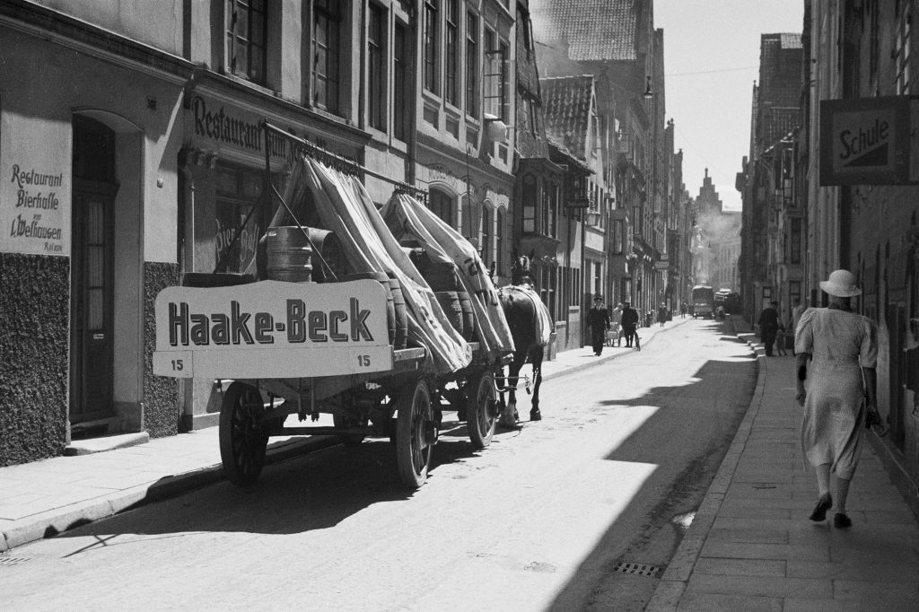 Blick in die Großenstraße. In der Straße steht ein Fuhrwerk mit einem Firmenschild von Haake-Beck. 