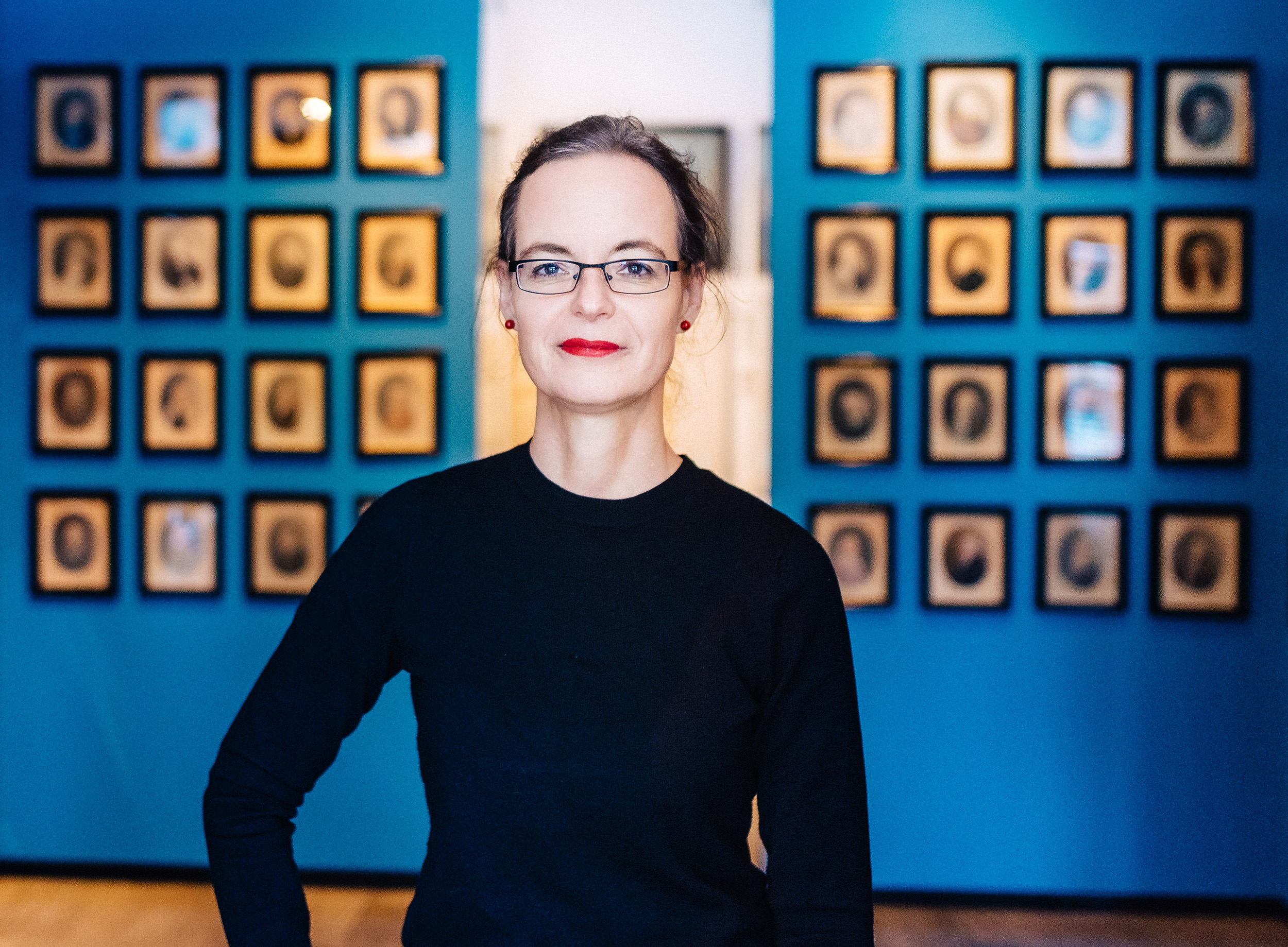 Direktorin Anna Greve steht vor Bildern des Wilcken'schen Kabinetts