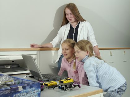 Drei Mädchen konstruieren einen Roboter mit Lego Mindstorms und programmieren ihn am Computer.
