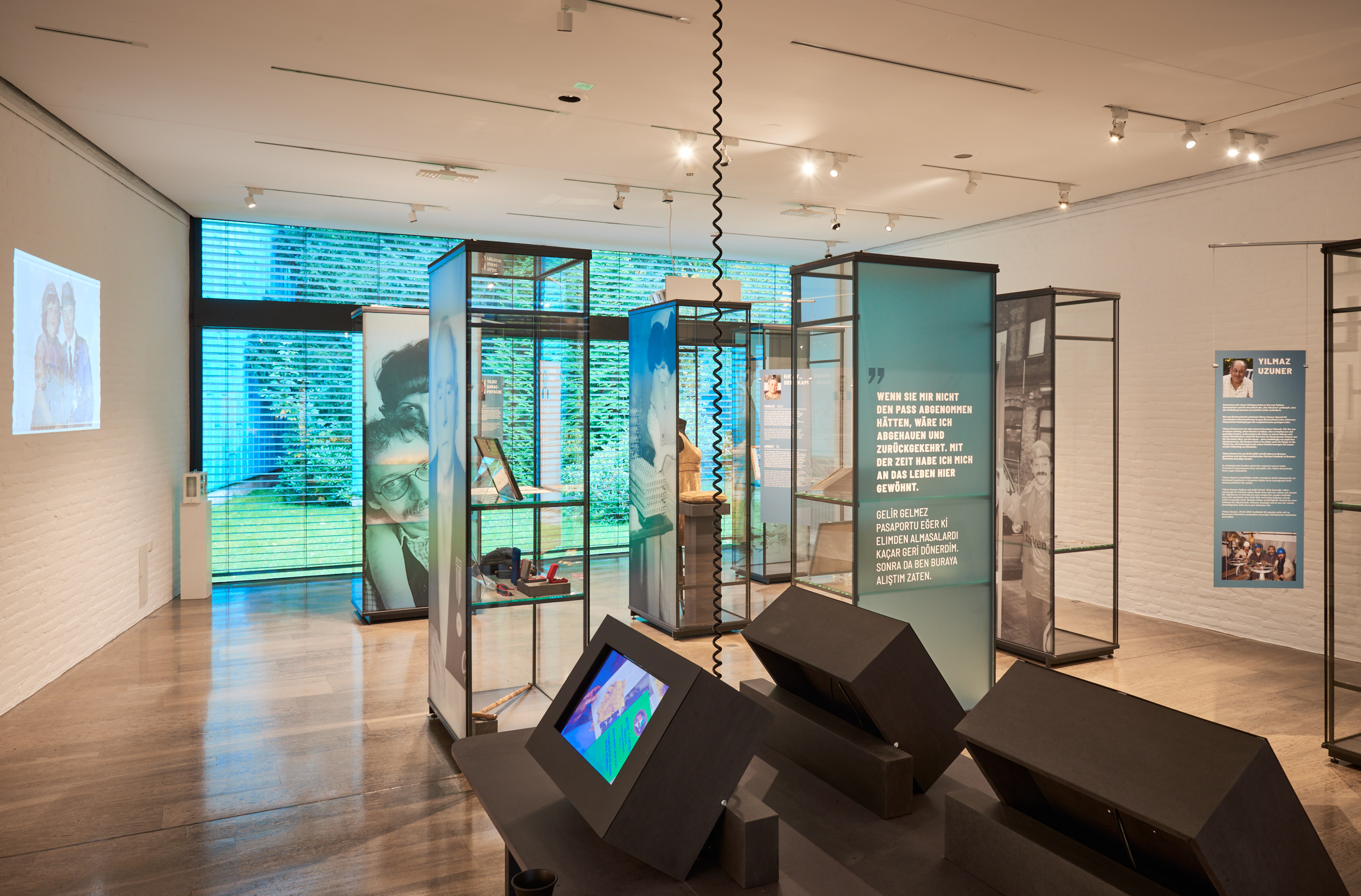 Blick in den Ausstellungsraum, zu sehen sind Vitrinen und Bildschirme. 