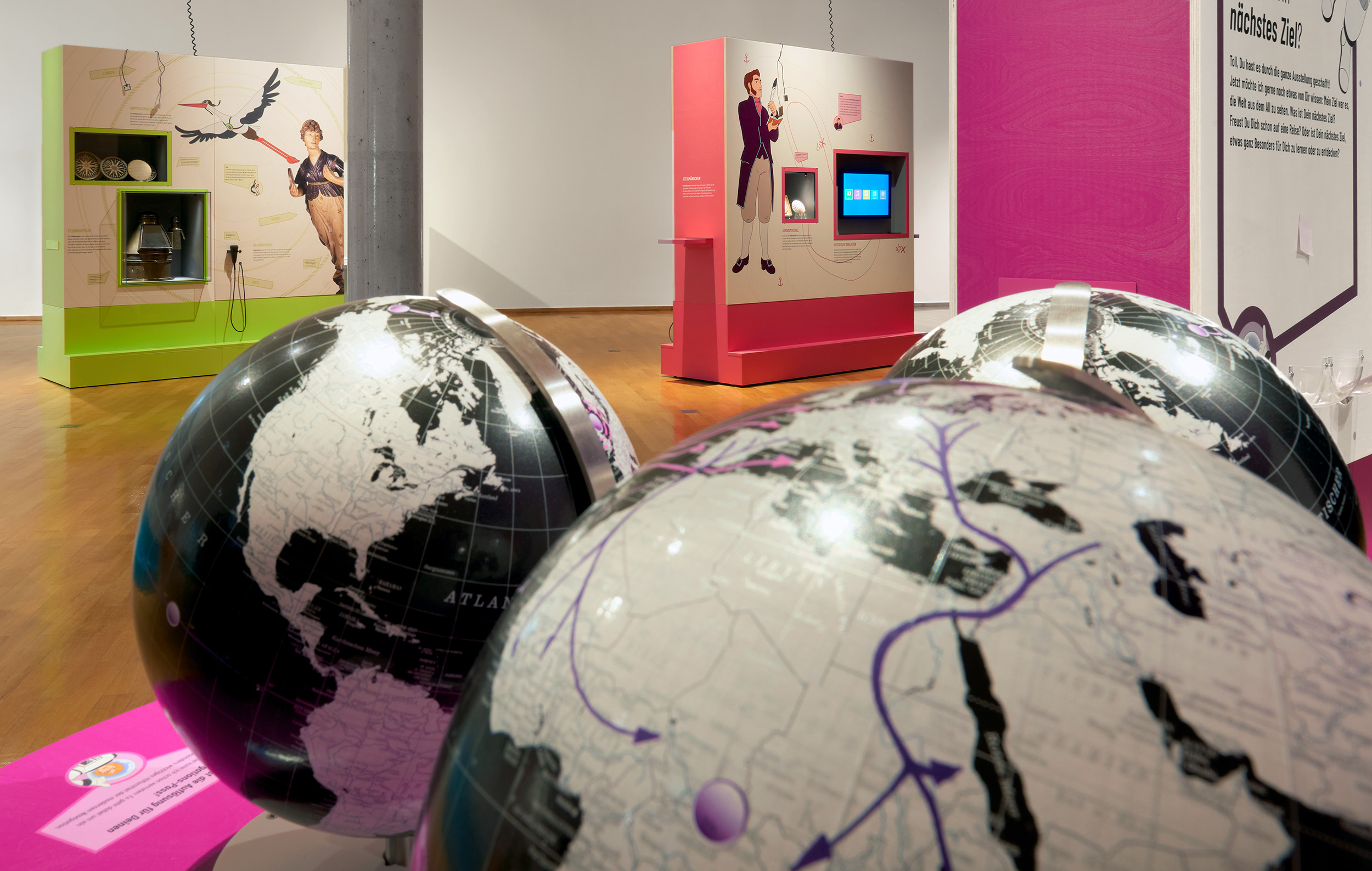 Im Vordergrund drei Globen, im Hintergrund farbige Ausstellungswände