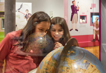 zwei Mädchen schauen sich einen Globus an