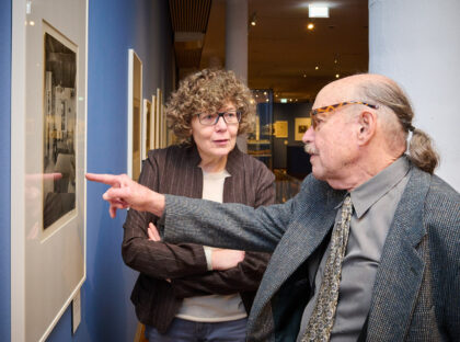 Michael Frank und Dr. Karin Walter stehen vor einem Foto von Julius Frank in der Ausstellung.