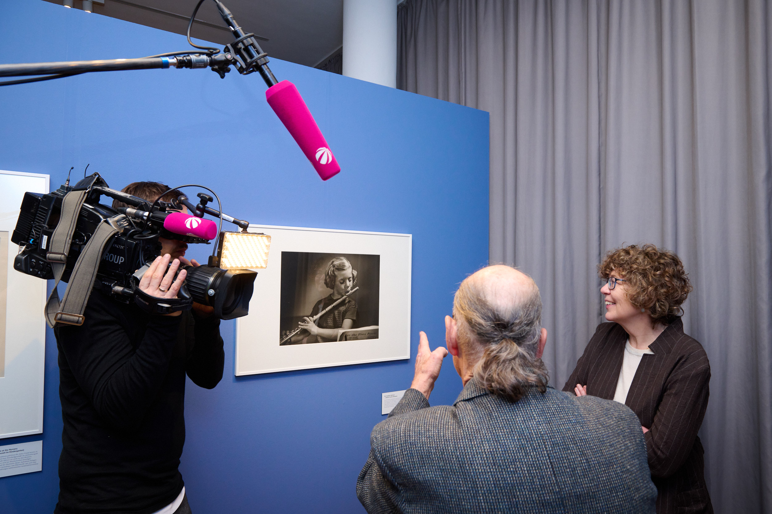 Mike Frank und Dr. Karin Walter schauen sich ein Bild an. Ein Fernsehteam filmt die Szene.