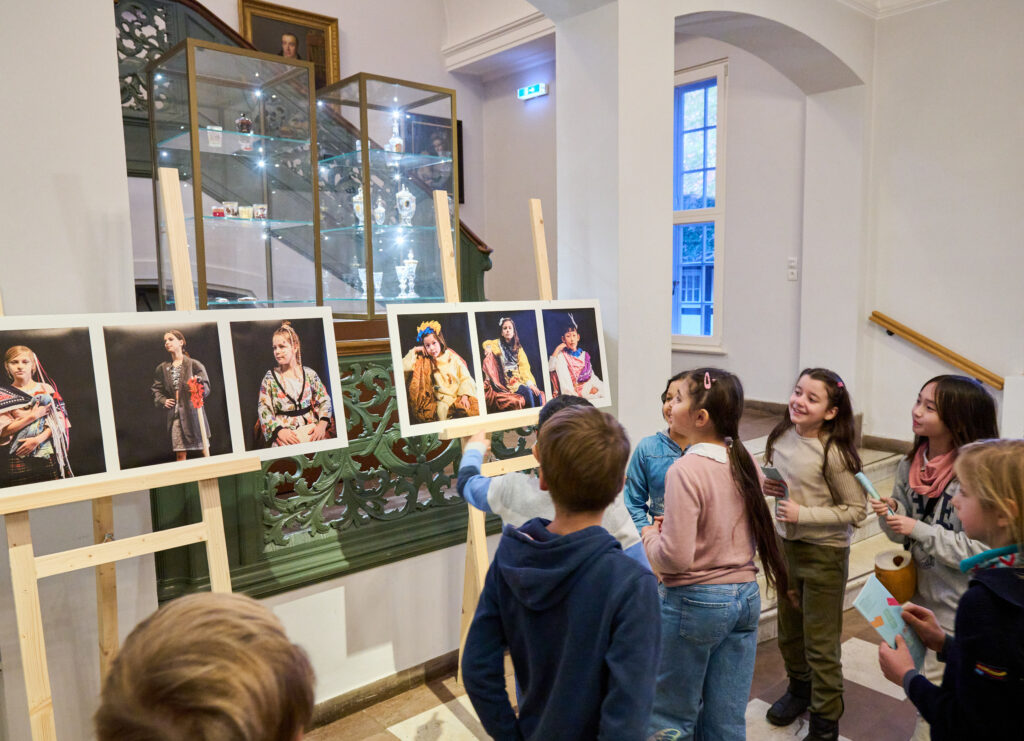 Kinder vor einer Fotogalerie im Treppenhaus von Haus Riensberg