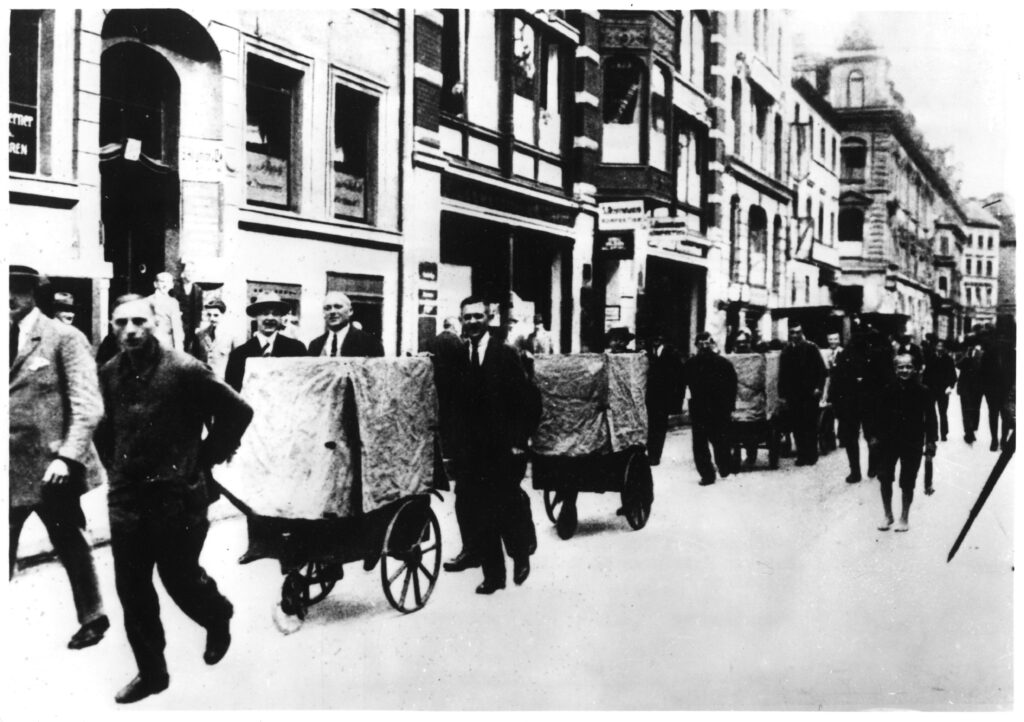 1923 werden durch eine Straße in Halle an der Saale mehrere Geldtransporter gezogen. Sie sind mit Tüchern verdeckt. 
(C) Deutsches Historisches Museum 