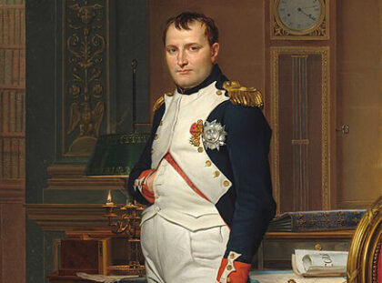 Gemälde von Napoleon. Er steh in Uniform in der Bibliothek und steckt seine Hand in seine Weste.