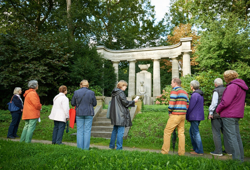 Menschengruppe vor einem Grabmal auf dem Riensberger Friedhof.