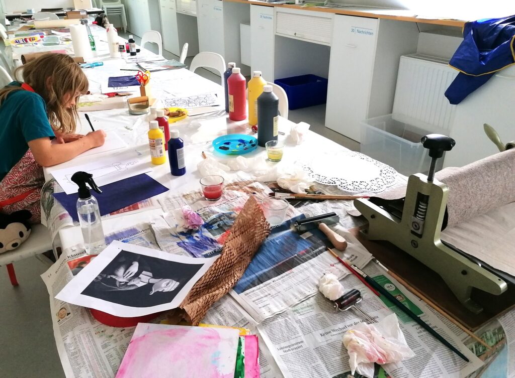 Blick auf einen Tisch mit Druckmaschinen und fertigen Drucken.